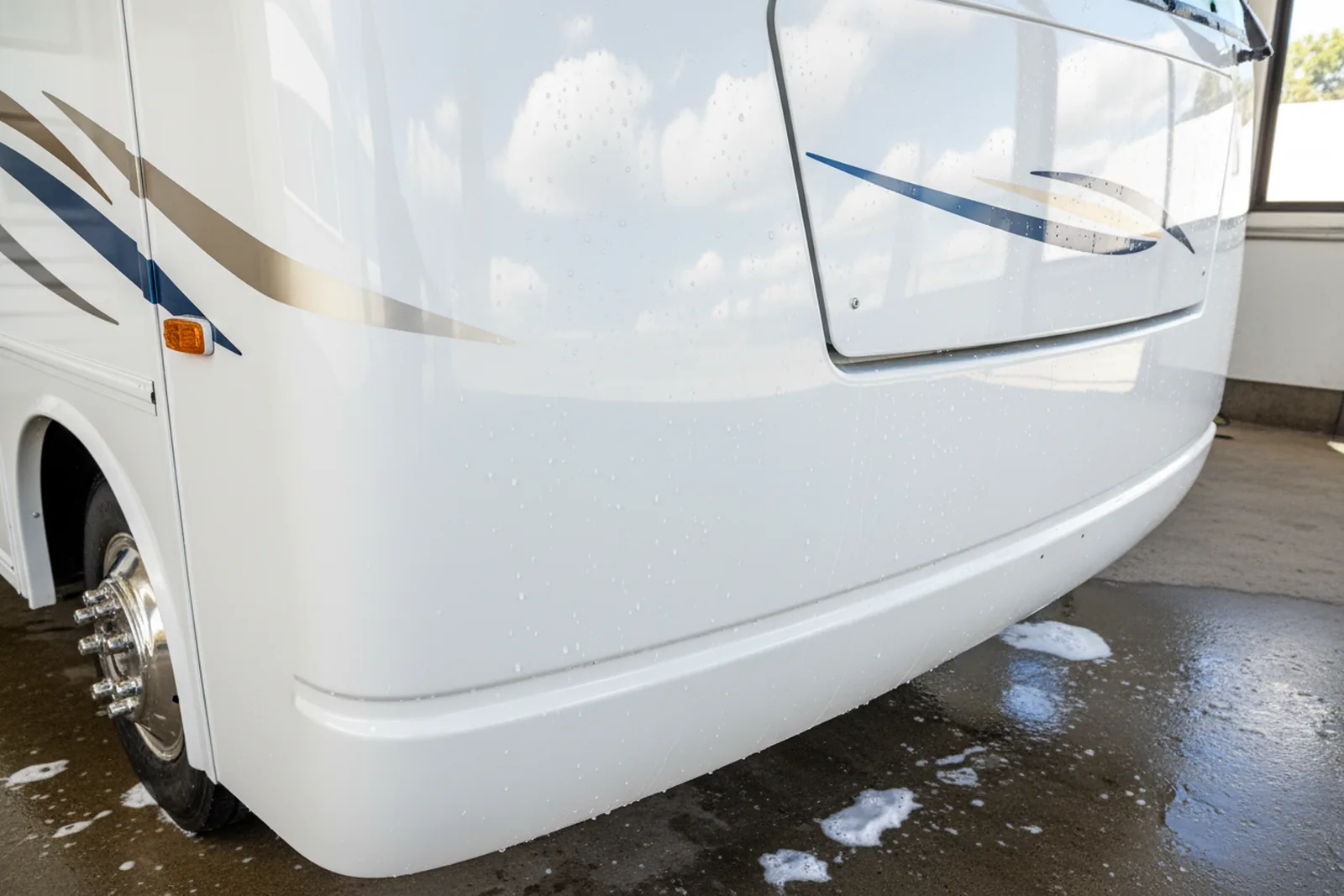 Glossy curved front cap of a white motorhome reflecting clouds after polishing, demonstrating RV exterior detailing.